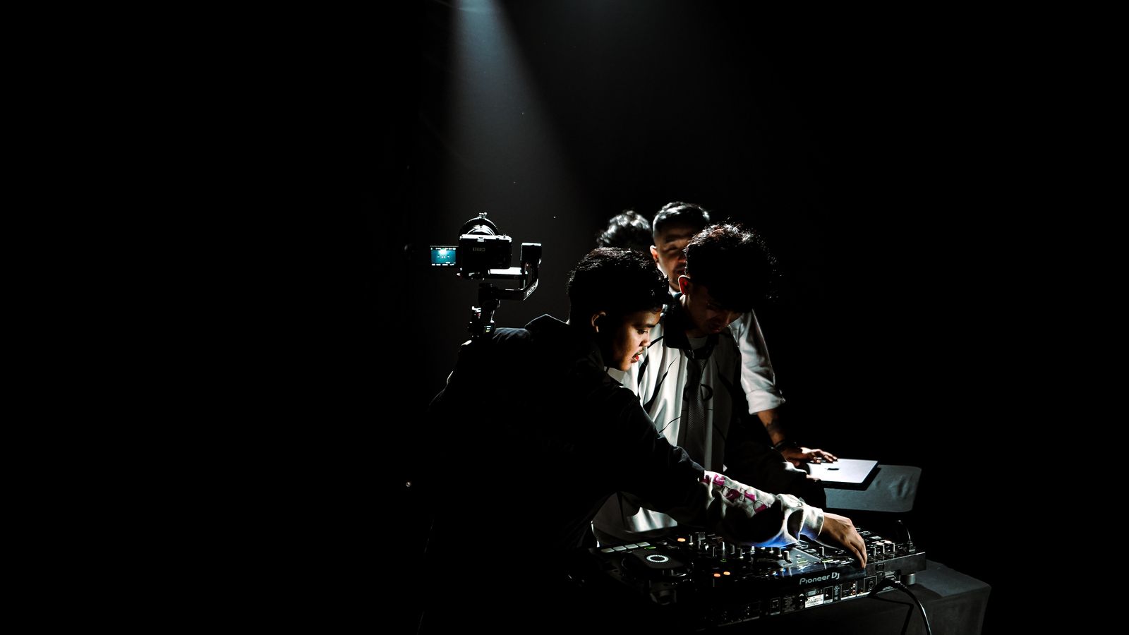TREF crew filming a DJ under a single spotlight