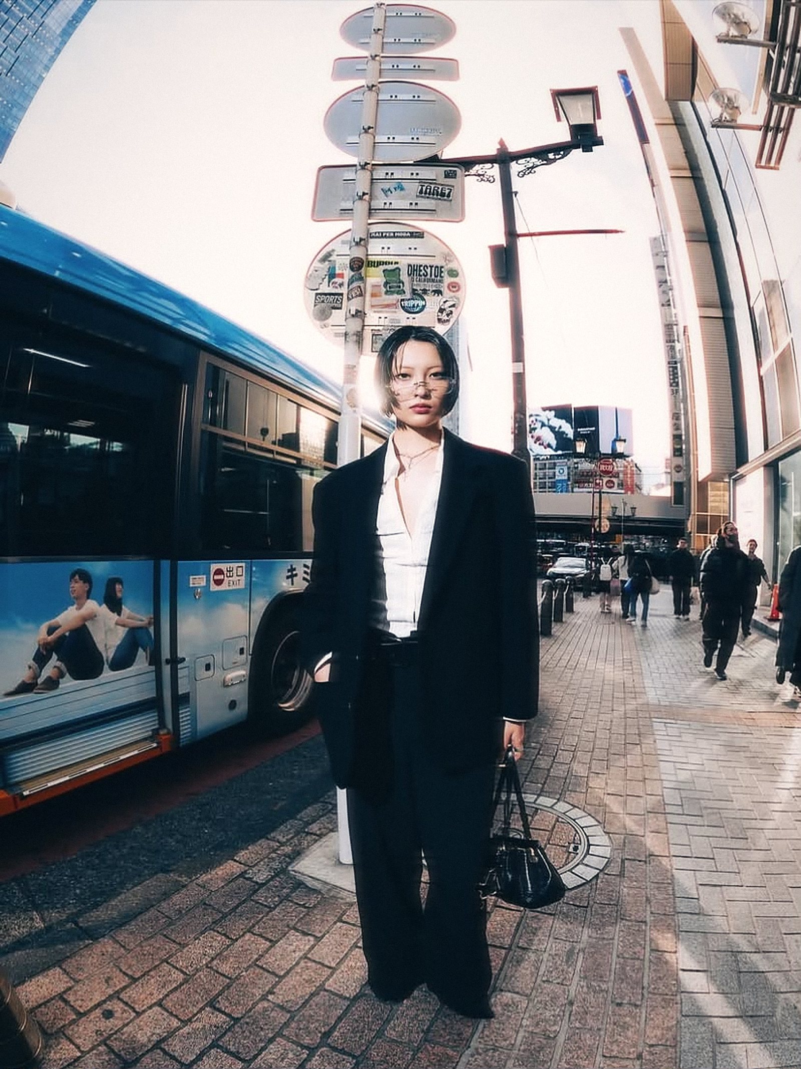 Model in a black suit next to a city bus in Shibuya